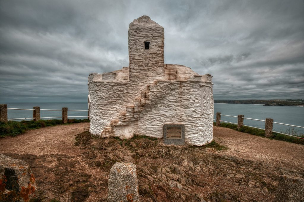 a stone structure sitting on top of a hill next to a body of water